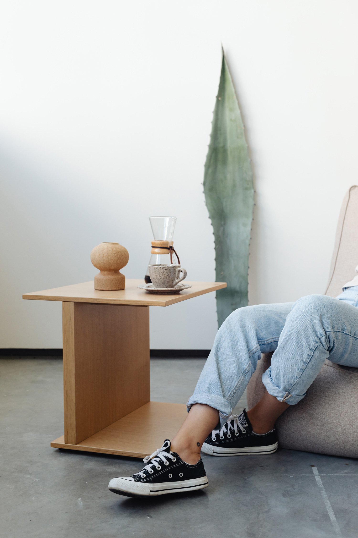 Detalle de mesa auxiliar y planta en habitación adolescente, diseño cálido y minimalista que transmite bienestar y calma.