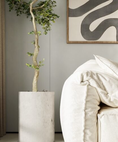 Planta interior junto a un sofá beige y un cuadro de líneas orgánicas. Espacio luminoso y natural.