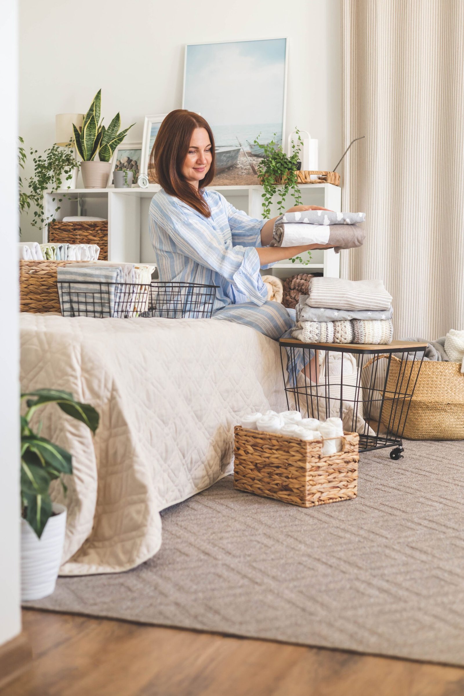 Dona doblegant roba en un dormitori lluminós, reflex de l’ordre conscient i del benestar que neix en simplificar.