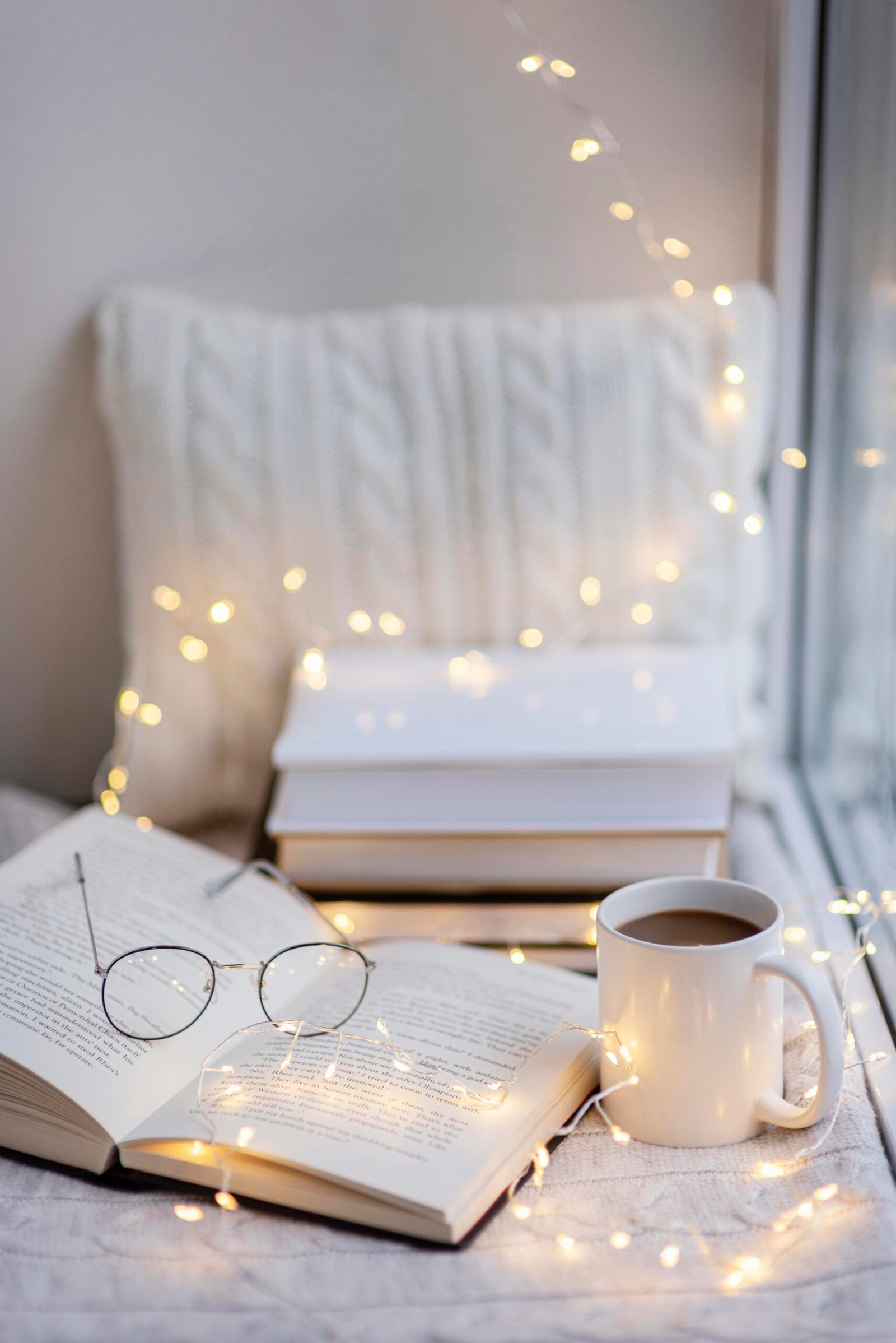 Libros, taza y luces cálidas creando un ambiente acogedor