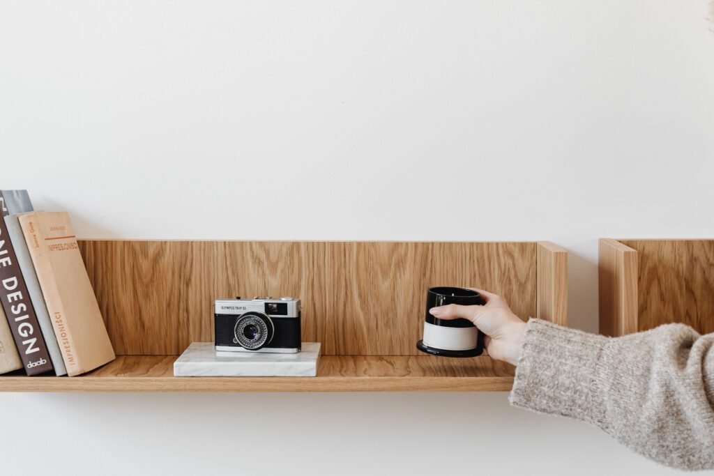 Mà col·locant una espelma en una prestatgeria de fusta amb llibres i una càmera decorativa.