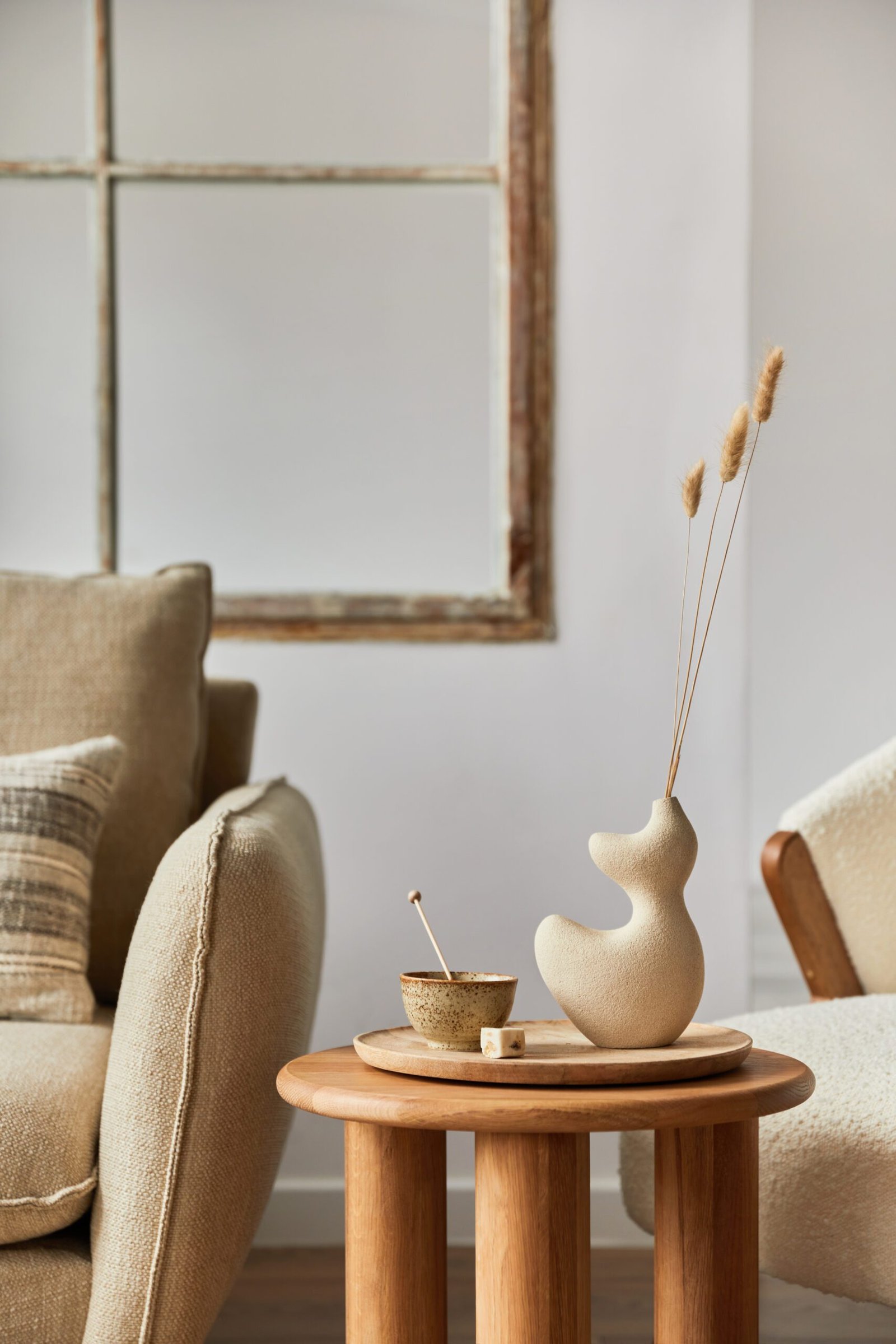 Rincón de estar con mesa auxiliar redonda y jarrón de formas orgánicas que aportan fluidez visual.