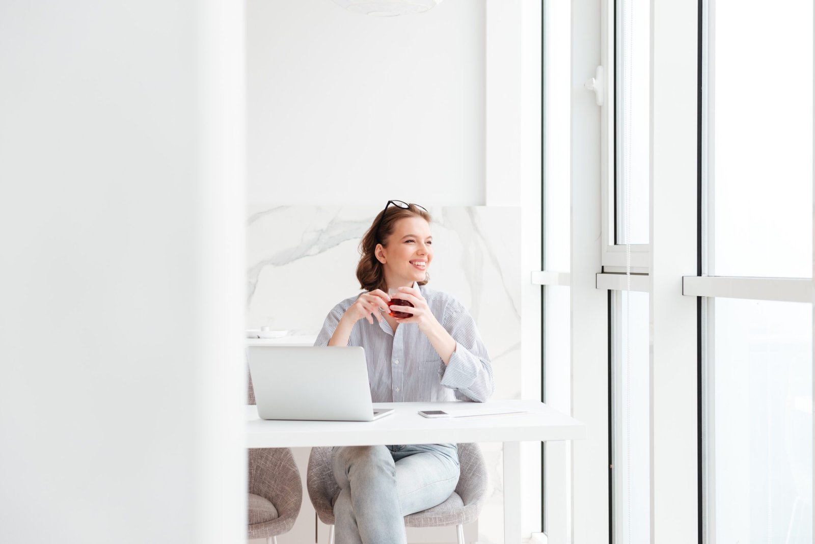 Mujer sonriendo con una taza de té en un ambiente de trabajo luminoso que transmite claridad mental y descanso