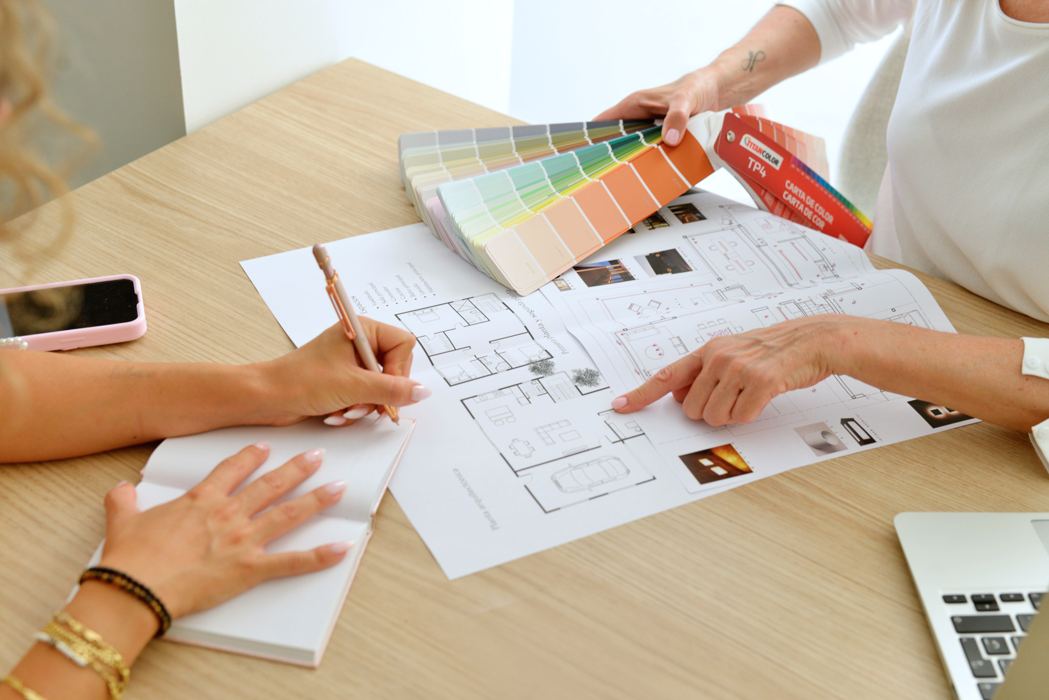 Manos revisando planos y paletas de color durante una asesoría de interiorismo.